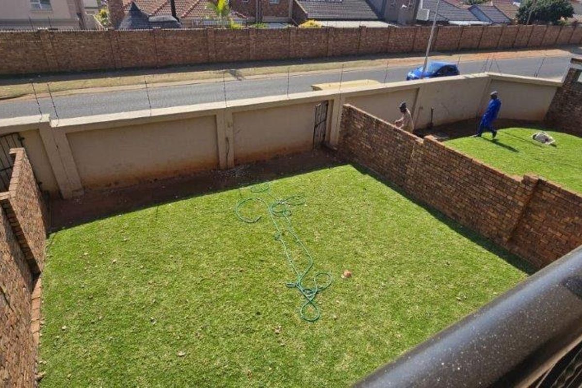 A private rear garden featuring a lawn area enclosed by brick boundary walls with integrated electric fencing.