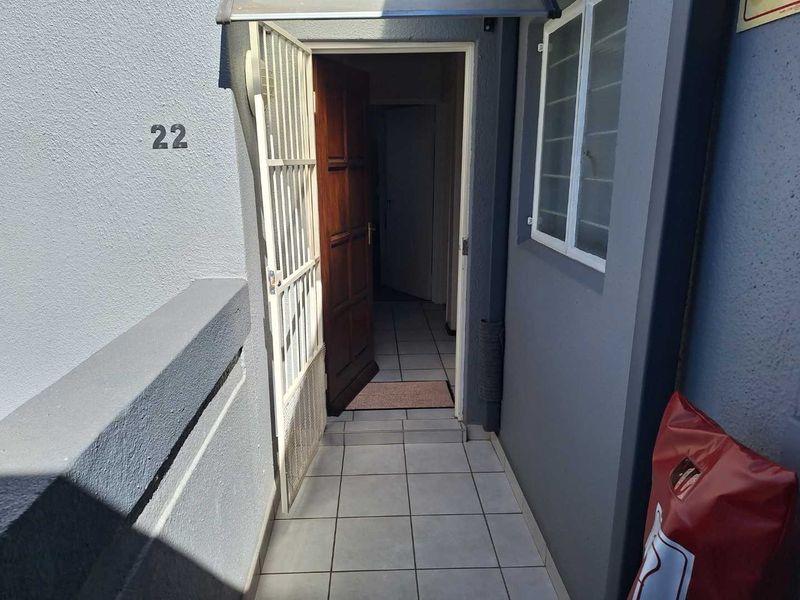 Entrance area of the townhouse featuring a security gate, tiled flooring, and a timber front door.