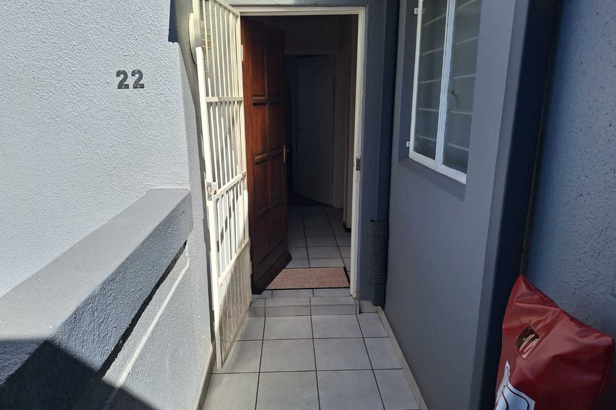 Entrance area of the townhouse featuring a security gate, tiled flooring, and a timber front door.