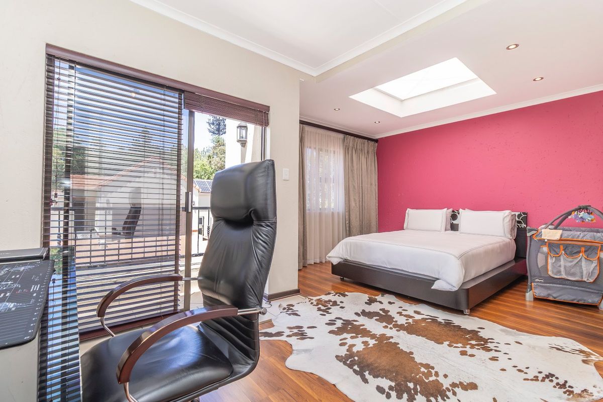 Spacious bedroom featuring laminate flooring, a large skylight, and a sliding glass door providing access to an outdoor balcony area.