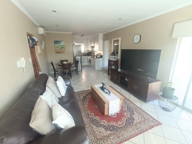 Open-plan living and dining area featuring tiled flooring, recessed lighting, and a seamless transition to the kitchen, with access to an outdoor space.