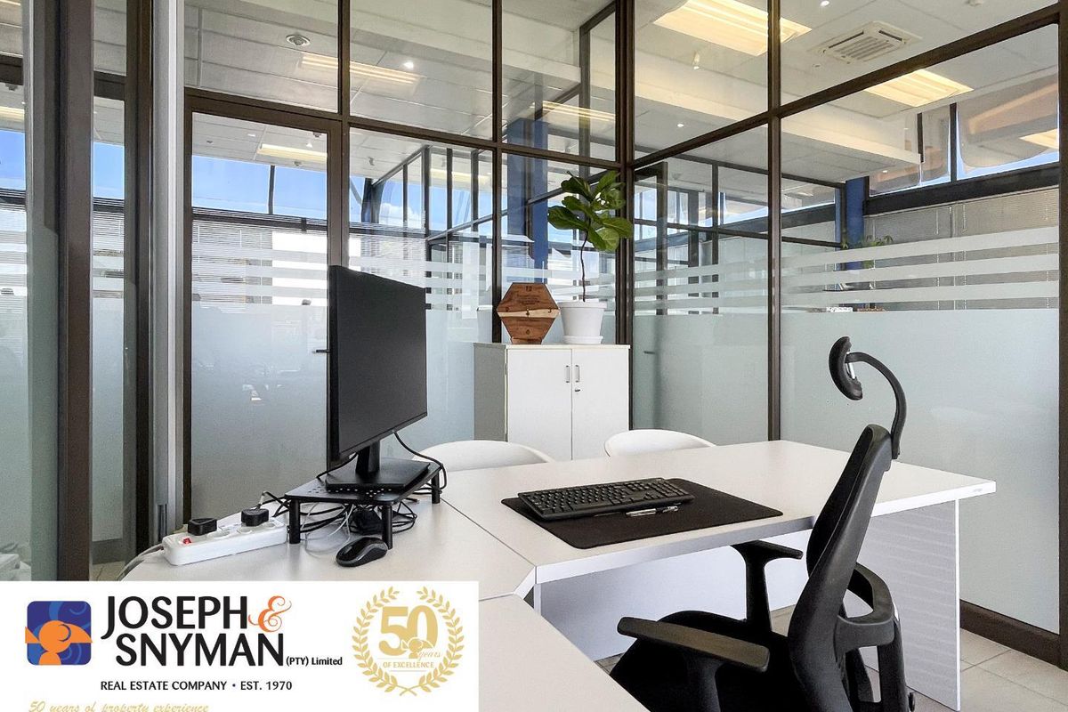 A modern office space featuring glass partitioning, drop ceiling with recessed lighting, and tiled flooring, providing a professional and bright work environment.