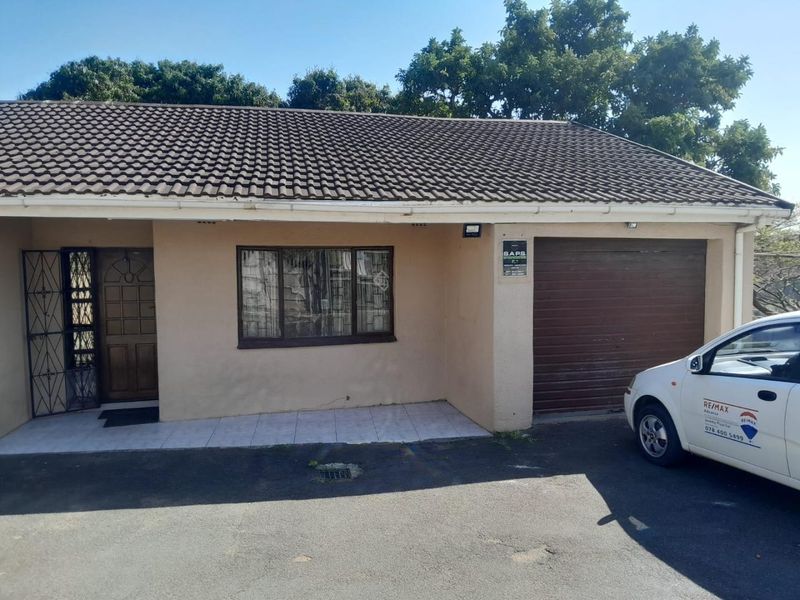Front elevation of a single-story house featuring a tiled roof, integrated garage, and a tiled entrance porch with security gate.