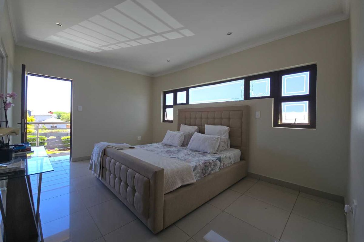 Spacious bedroom featuring large format floor tiles, recessed lighting, and a sliding door providing access to an outdoor balcony area.