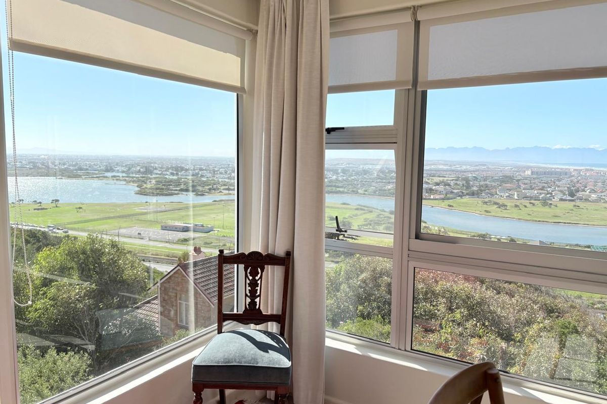 A bright corner living area featuring expansive floor-to-ceiling windows that offer panoramic views of the surrounding landscape and water.