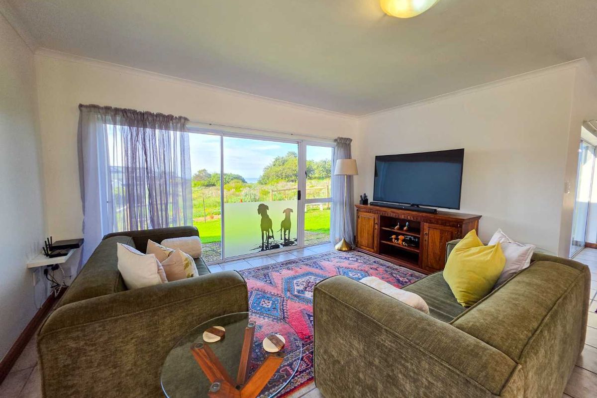 A comfortable living room featuring tiled flooring and a large sliding glass door that provides natural light and access to the outdoor area.