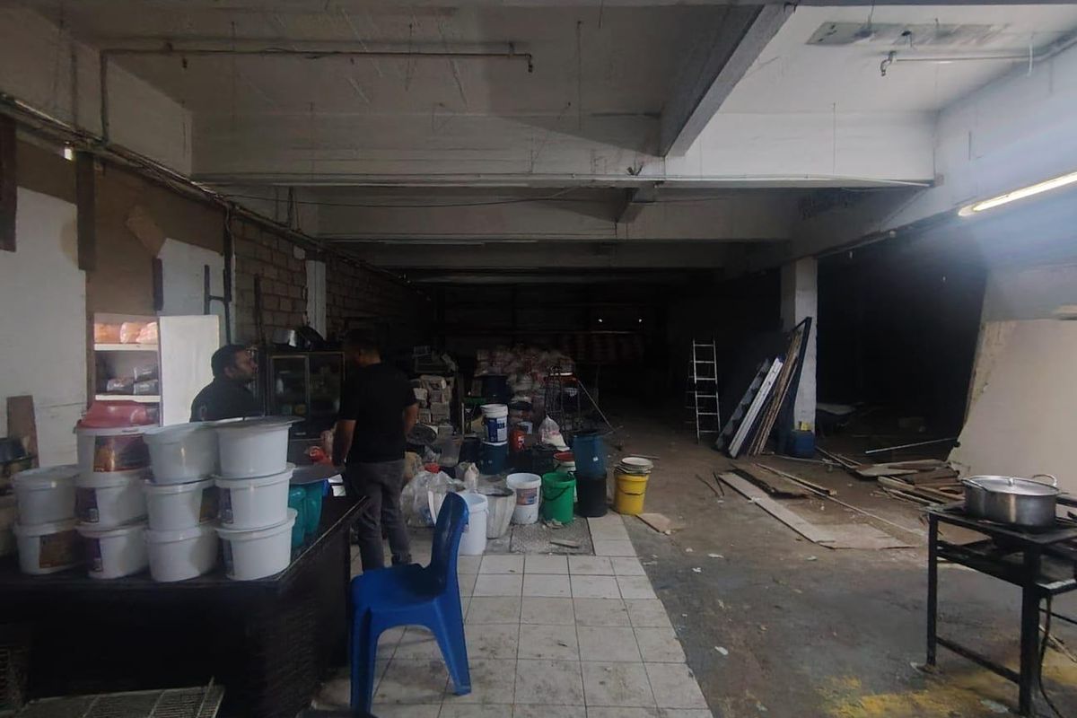 Large industrial utility space featuring exposed concrete structural elements, tiled flooring, and unfinished brick walls, suitable for storage or workshop use.