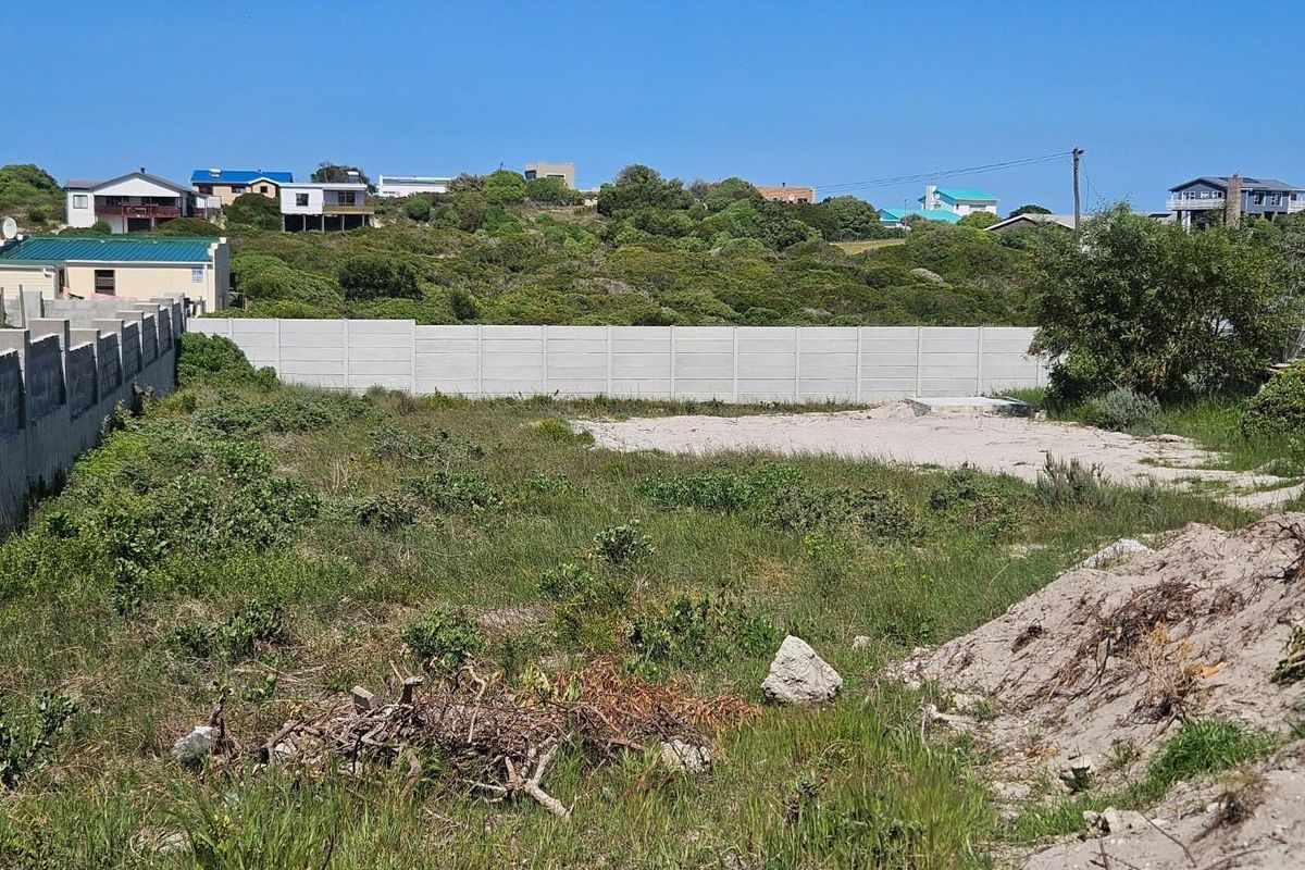 A vacant residential plot featuring perimeter concrete walling and natural coastal vegetation, offering a blank canvas for future development.