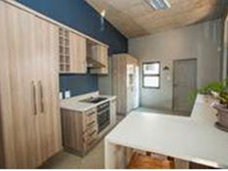 Modern kitchen featuring light wood cabinetry, stone countertops, integrated oven, hob, extractor fan, and a functional breakfast bar area.