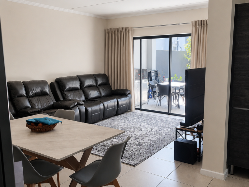 Open plan living and dining area featuring neutral tiled flooring and large sliding glass doors providing access to an outdoor patio space.