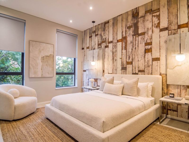 A well-appointed bedroom featuring a textured wood-look feature wall, recessed downlighting, and large windows with roller blinds, creating a bright and modern atmosphere.