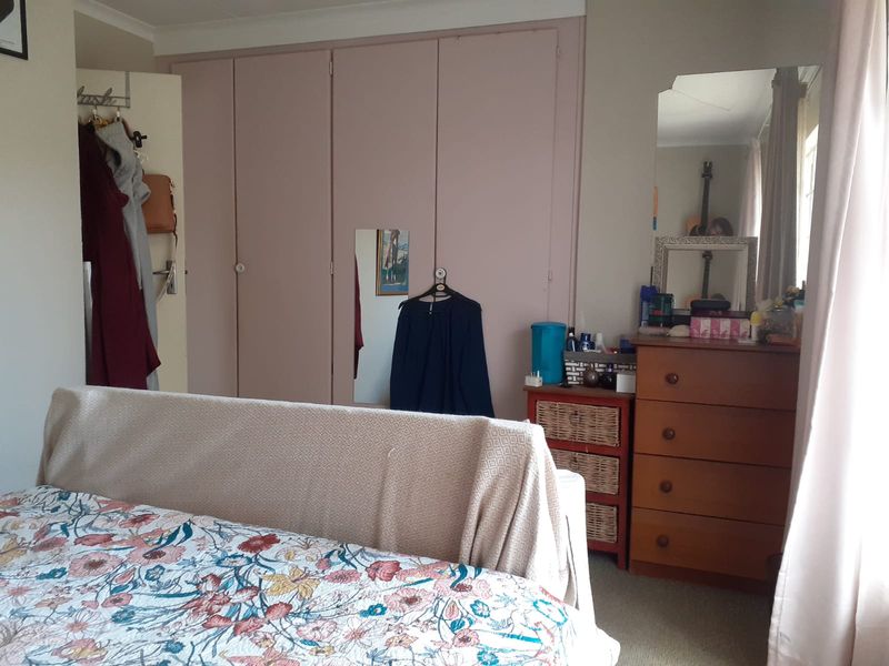 A bedroom featuring built-in wardrobes and carpeted flooring, offering a functional space with potential for cosmetic updates.
