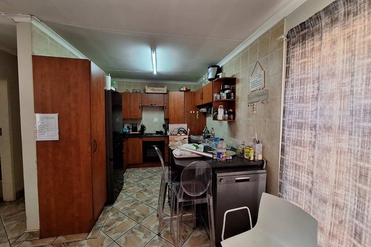 A functional kitchen featuring wood-look cabinetry, tiled backsplash, and integrated oven and hob, offering a practical layout for daily meal preparation.
