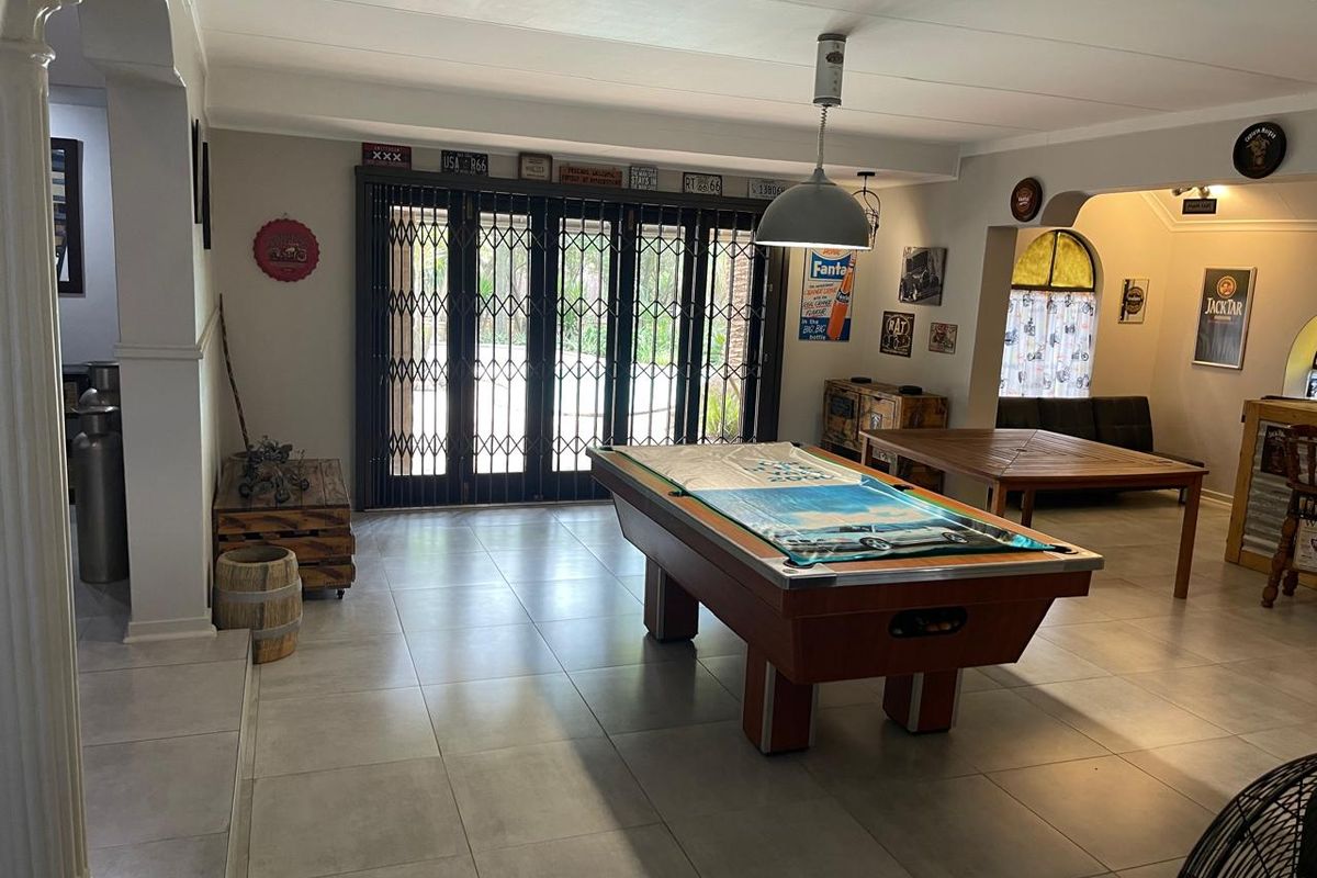 Spacious living area featuring large tiled flooring and secure folding security gates leading to the outdoor patio area.