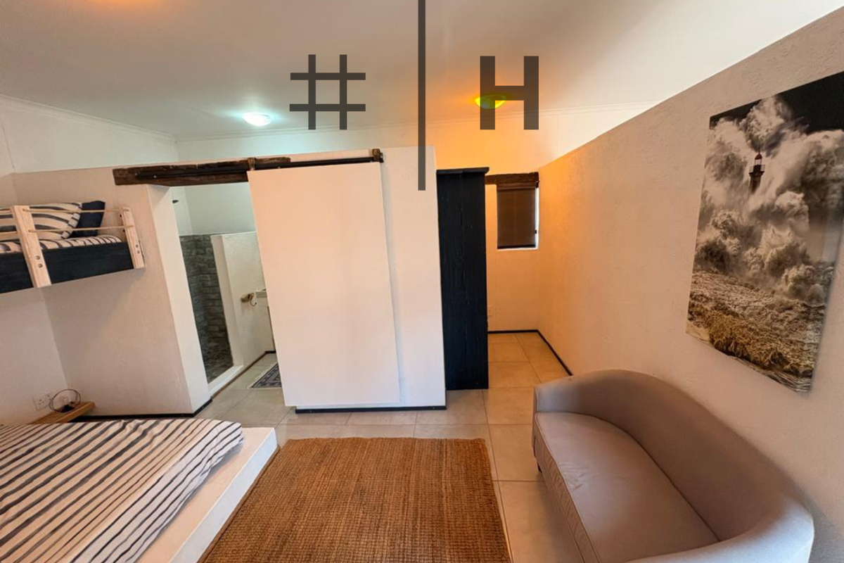 Bedroom featuring tiled flooring, an exposed timber beam, and a sliding barn door providing access to an en-suite bathroom area.