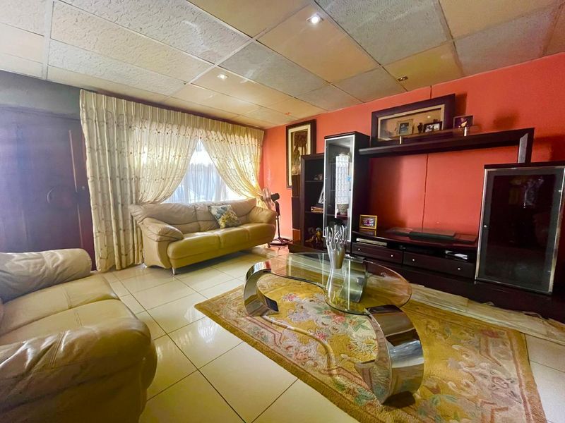 A living room featuring tiled flooring and a suspended ceiling with recessed lighting, offering a dated aesthetic ready for modernization.