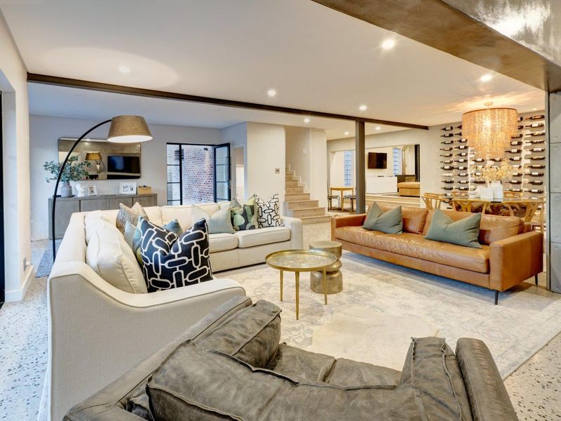 Spacious open-plan living area featuring terrazzo flooring, exposed steel beams, and a dedicated built-in wine storage wall, creating a modern and sophisticated atmosphere.