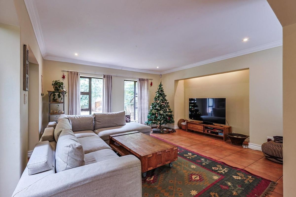 A comfortable living room featuring terracotta floor tiles, recessed lighting, and a built-in alcove for media storage.
