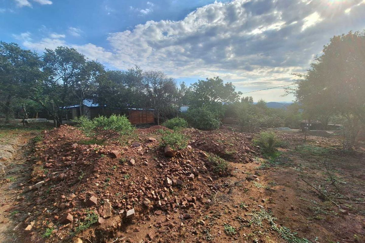 A view of the undeveloped residential land featuring natural terrain, mature trees, and uneven ground.