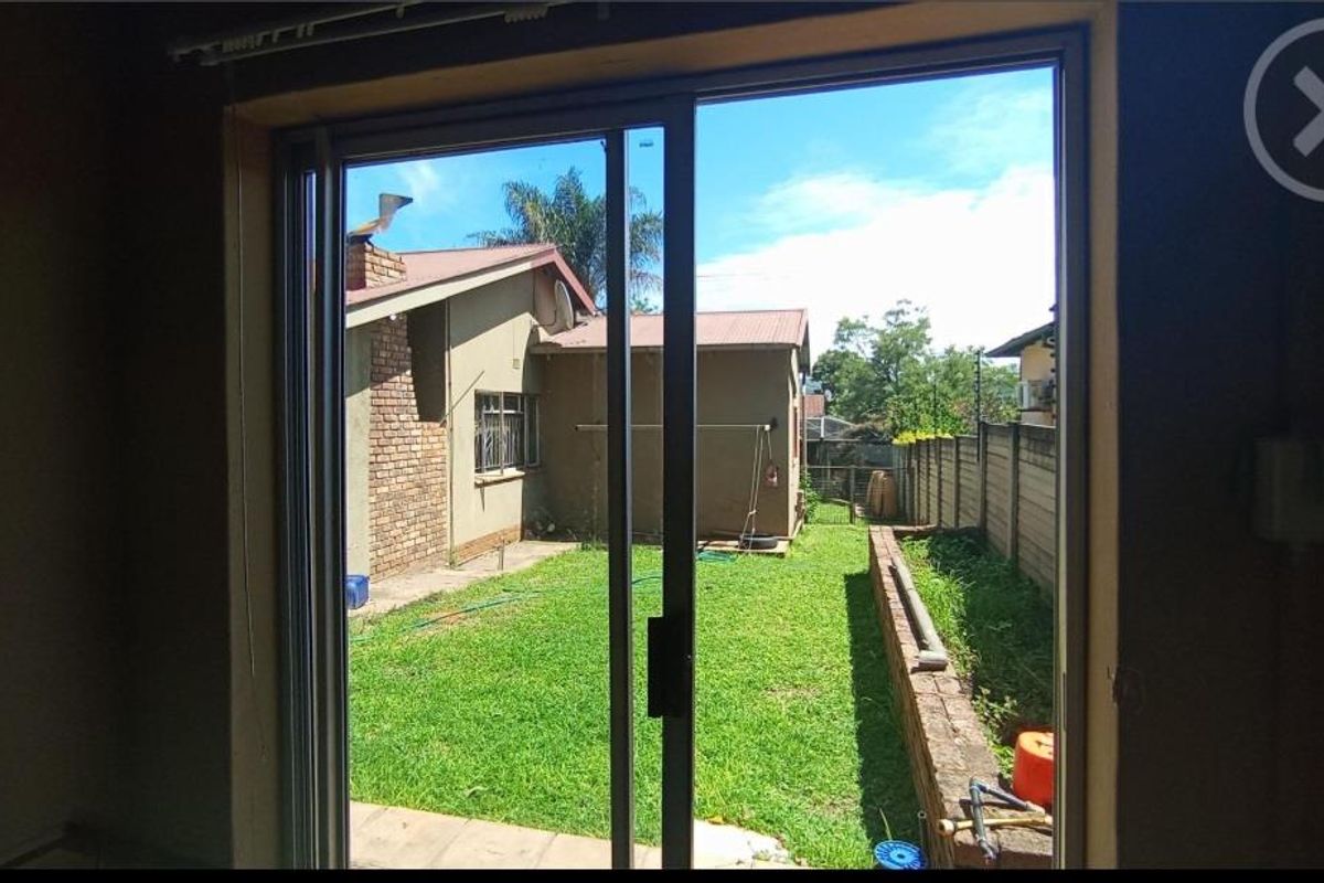View from an interior space looking out onto a private rear garden with a lawn and perimeter walling.