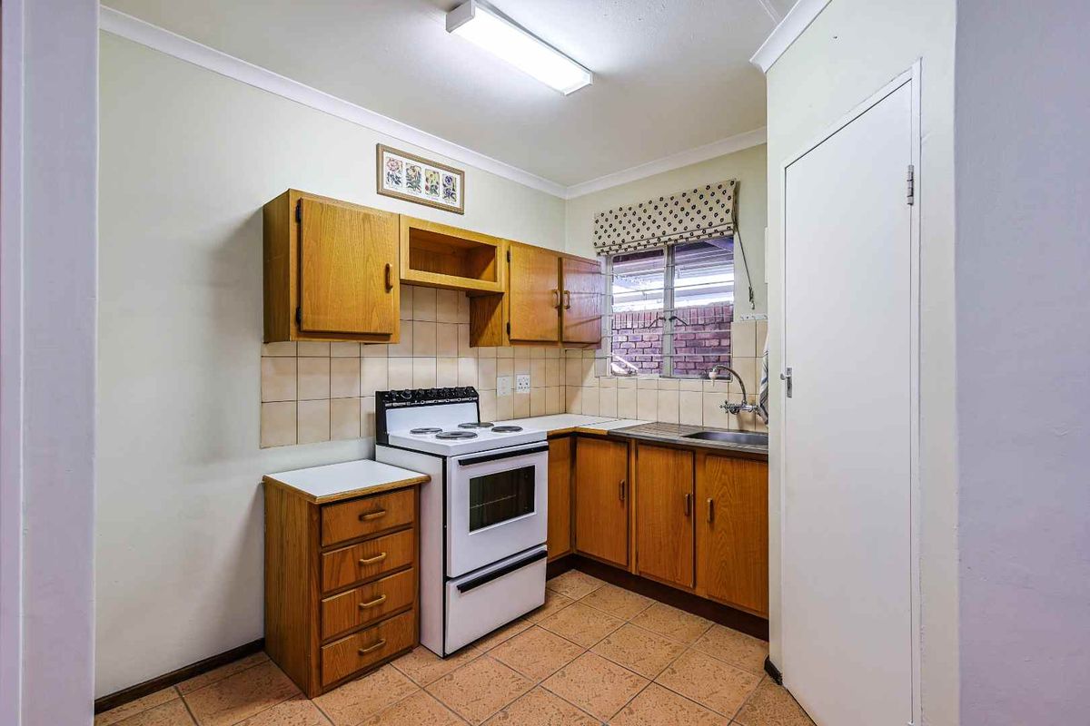 A functional kitchen featuring wooden cabinetry, a tiled backsplash, a freestanding stove, and a stainless steel sink.