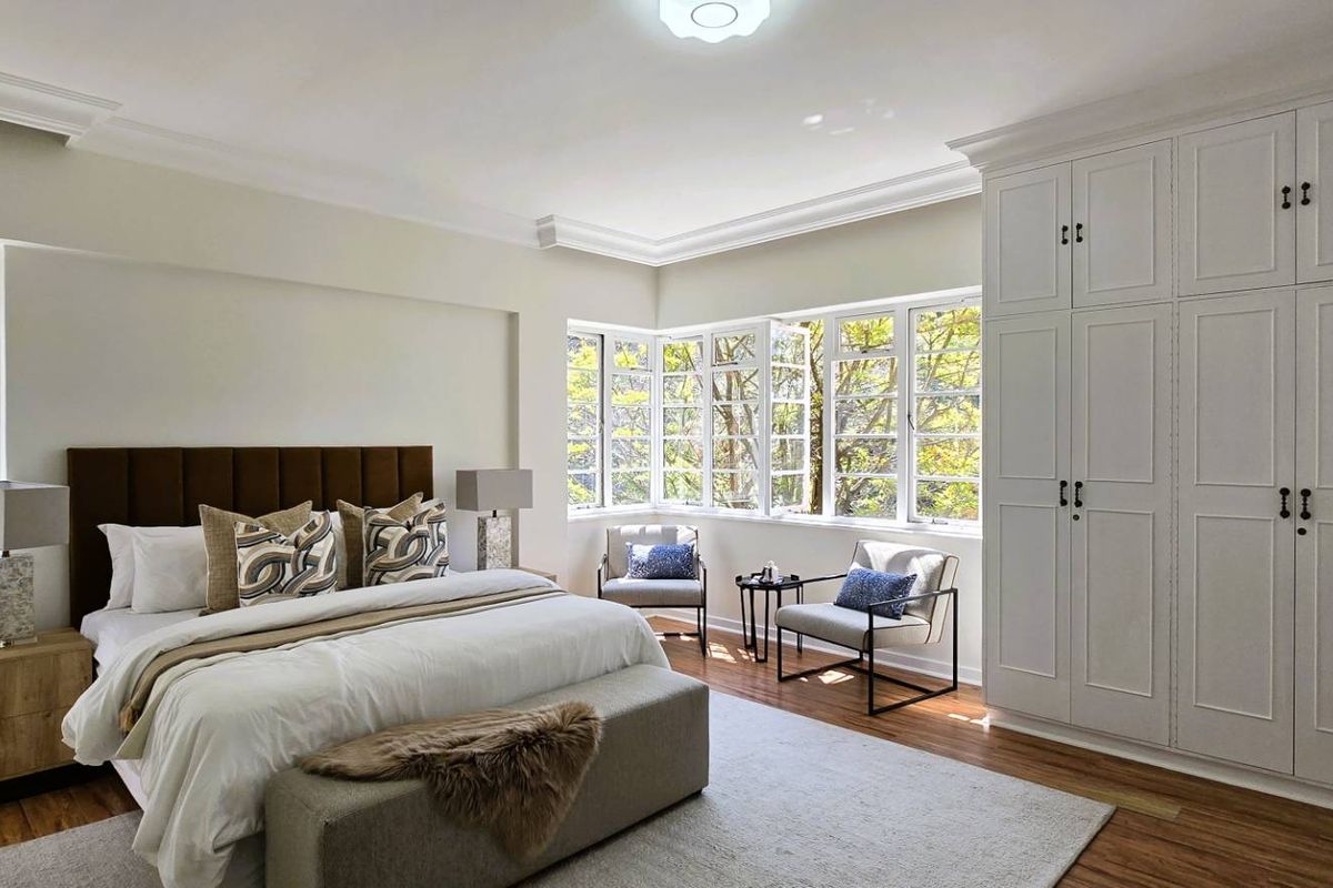 Spacious bedroom featuring extensive built-in cabinetry, hardwood flooring, elegant crown molding, and large windows providing ample natural light.