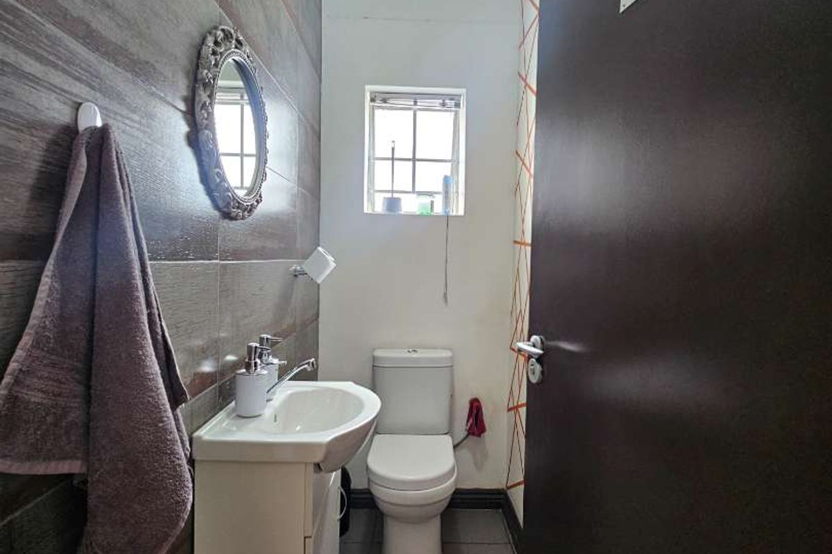 A compact office restroom featuring a modern vanity basin, toilet, and tiled wall finishes.