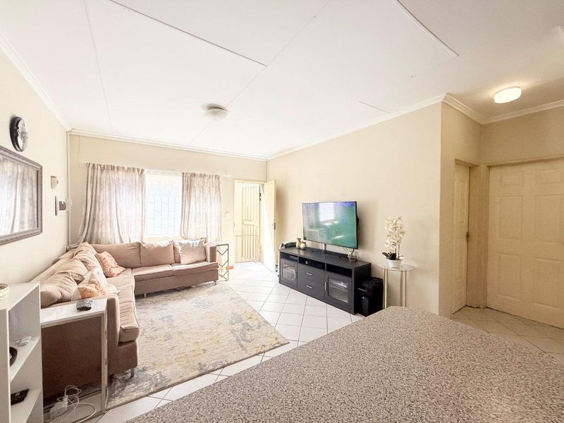 Open plan living area featuring tiled flooring, neutral walls, and direct access to the exterior via a security gate.