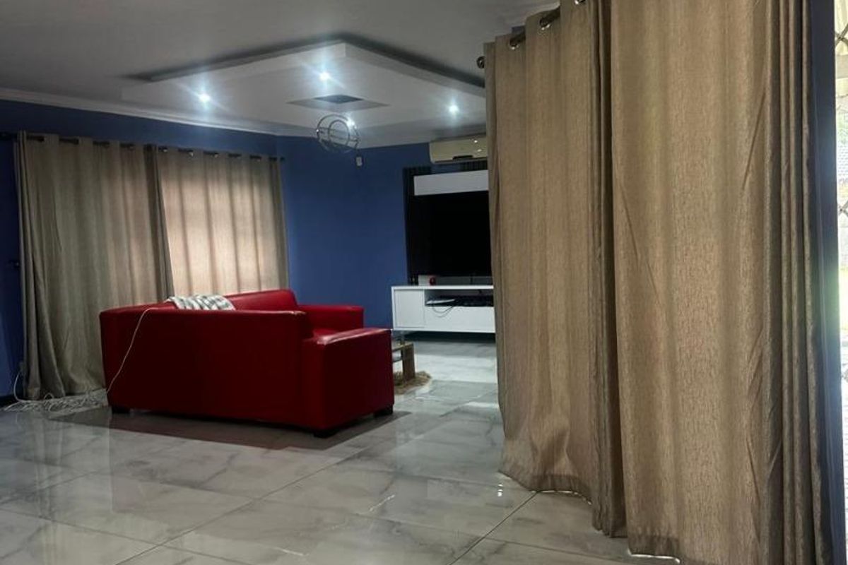 Spacious living room featuring polished porcelain floor tiles, a modern recessed ceiling with cove lighting, and an integrated air conditioning unit.