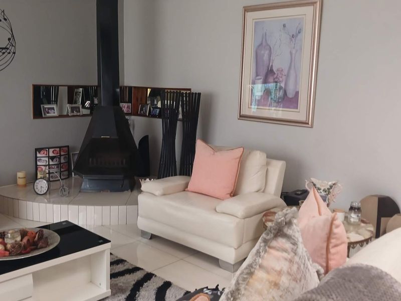 Living room featuring a black freestanding fireplace set on a raised tiled hearth with neutral floor tiles throughout.