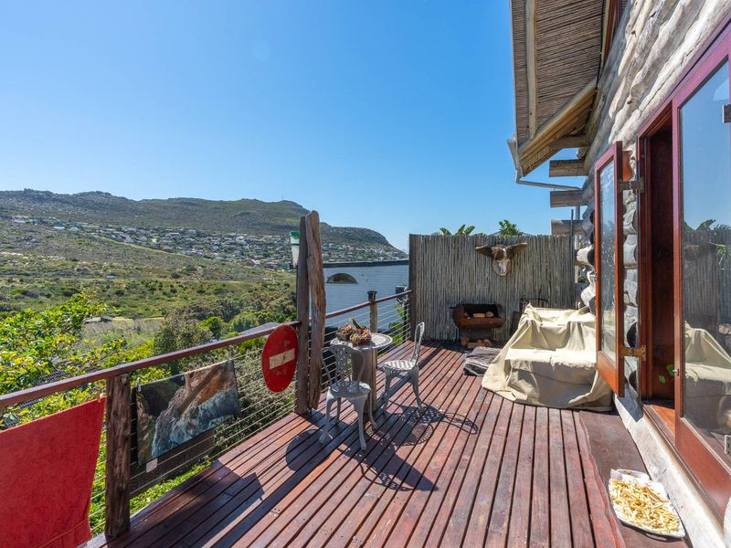A rustic timber balcony featuring a wire balustrade and expansive hillside views, providing an ideal outdoor space for relaxation.