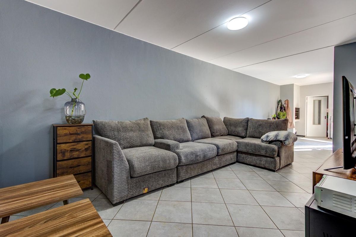 A spacious living area featuring neutral grey walls and tiled flooring, providing a clean and functional foundation for the home's main living space.