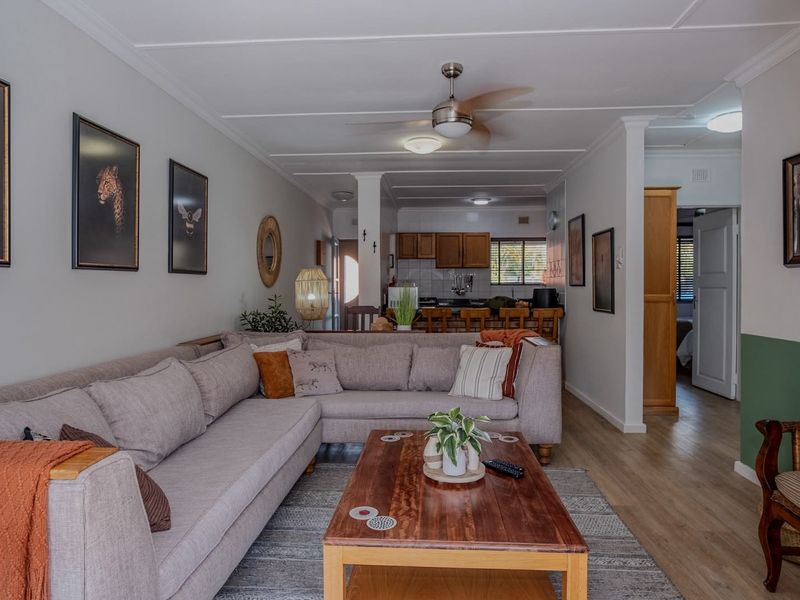 Spacious open-plan living area featuring laminate flooring, a ceiling fan, and a functional kitchen with a breakfast bar.