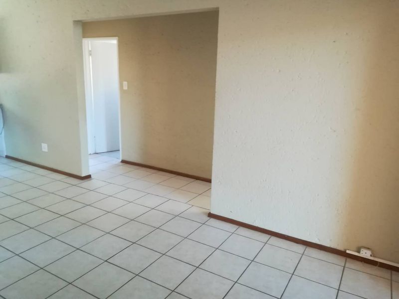 An empty living area featuring neutral ceramic floor tiles and textured walls, providing a blank canvas for potential interior design and renovation.
