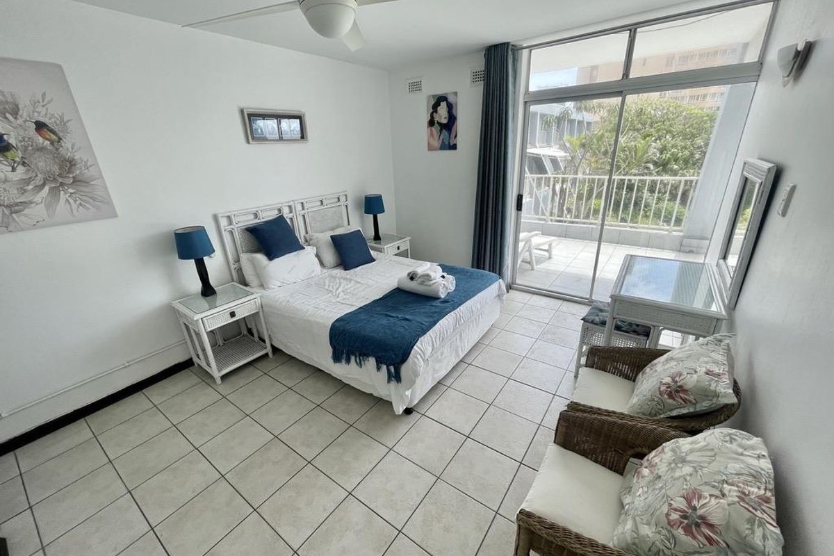 Spacious bedroom featuring tiled flooring, a ceiling fan, and large sliding glass doors providing direct access to a private balcony.