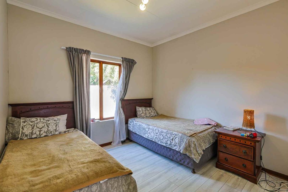 A bedroom featuring light-toned wood-look flooring, neutral wall paint, and a window with natural light.