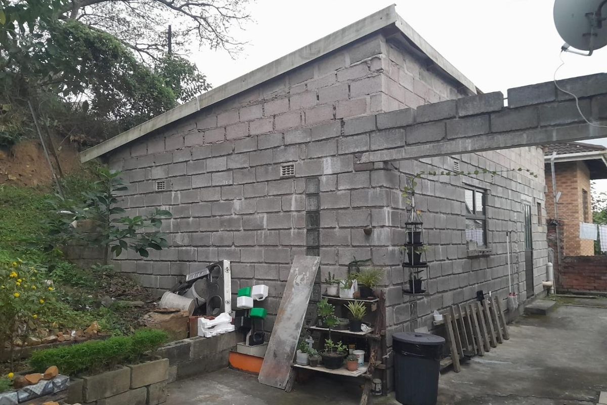 Rear view of a property featuring unfinished concrete block walls and a concrete paved area.