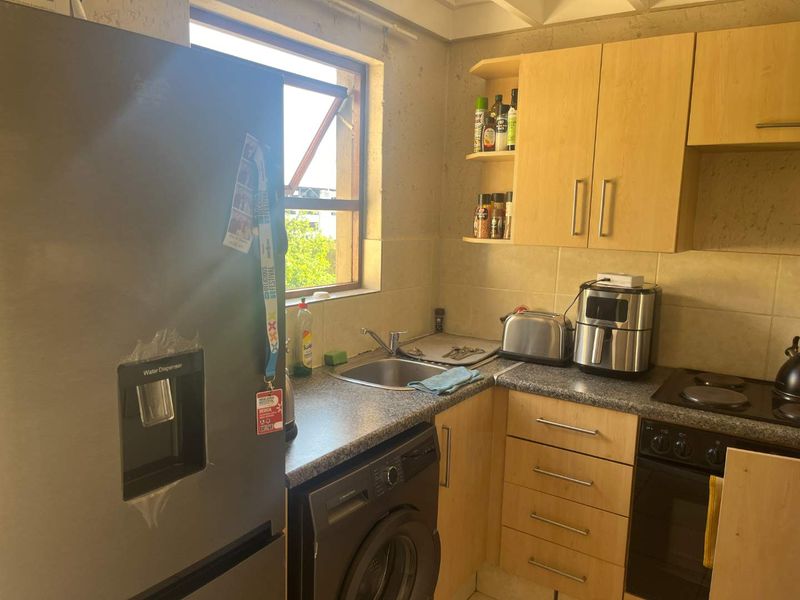 Compact kitchen featuring laminate cabinetry, granite countertops, built-in oven, hob, and integrated laundry plumbing, requiring cosmetic updates to the wall finishes.