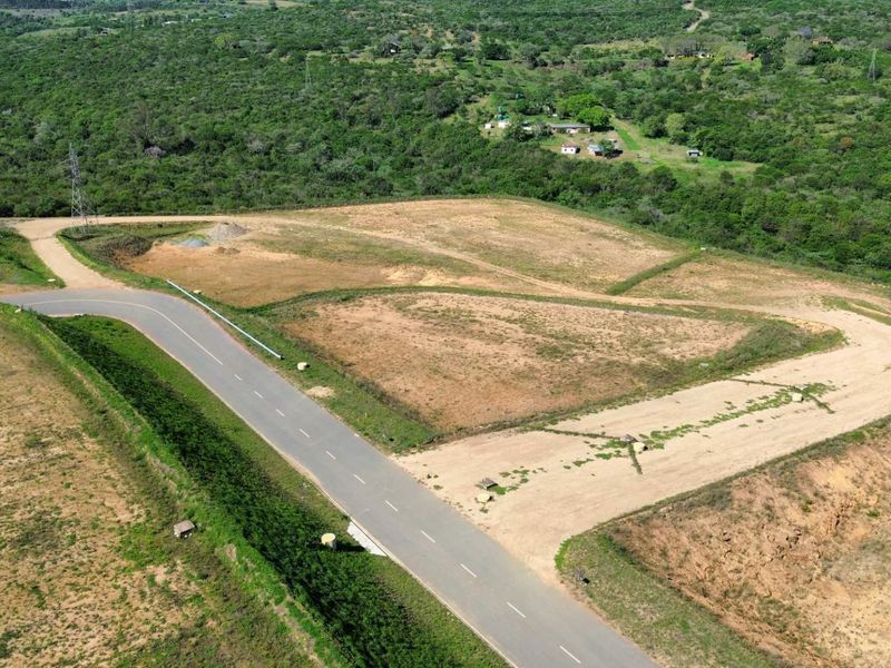 Aerial view of a cleared industrial plot featuring paved road access and surrounding natural landscape.