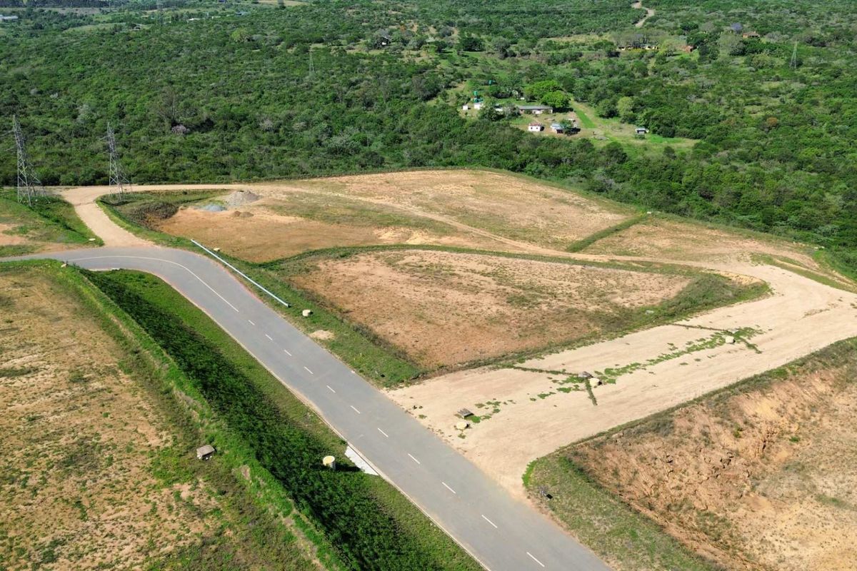 Aerial view of a cleared industrial plot featuring paved road access and surrounding natural landscape.