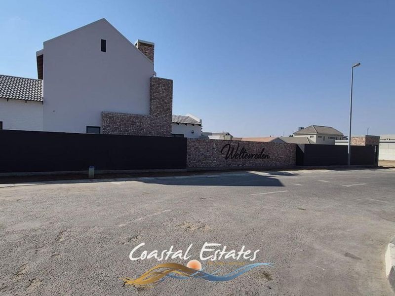 Street view of the Weltevreden estate entrance featuring modern boundary walls with stone cladding and paved access area.