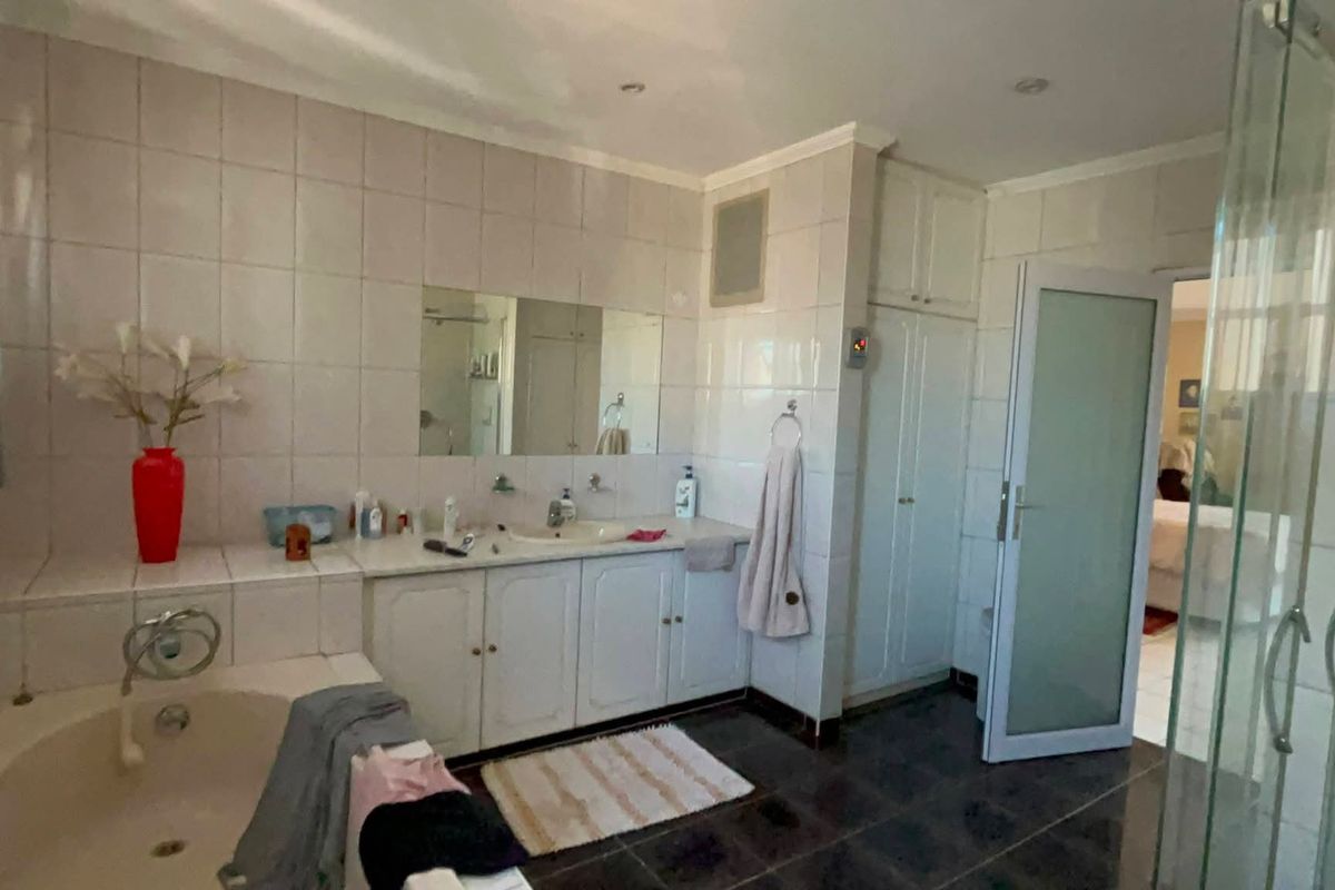 A functional bathroom featuring a built-in vanity, bathtub, separate glass shower enclosure, and tiled finishes throughout.