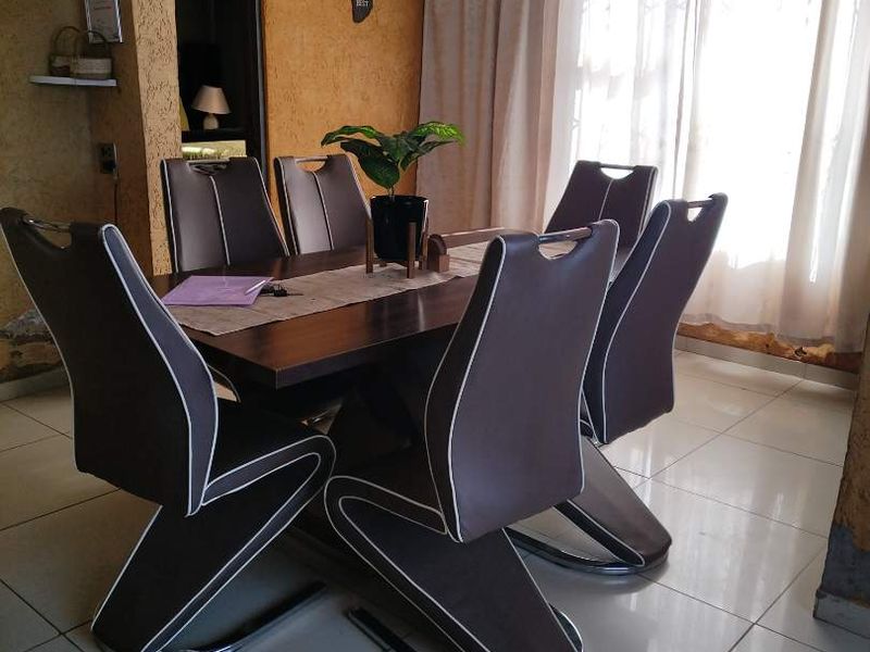 Dining room featuring tiled flooring, textured walls, and a central chandelier, with visible wear to the lower wall finishes.