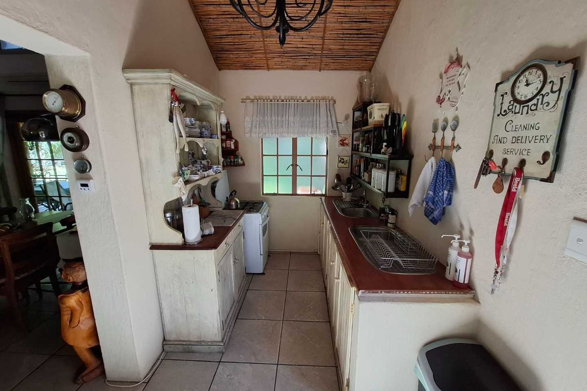 A compact, rustic-style kitchen featuring tiled flooring, built-in cabinetry, a gas stove, and a distinctive bamboo-style ceiling finish.