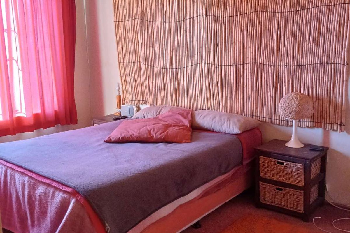 A bedroom featuring a wall-mounted bamboo decorative panel, wall-mounted air conditioning unit, and carpeted flooring.