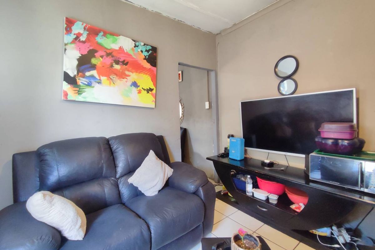 A compact living room featuring tiled flooring and neutral wall tones, providing a functional space for relaxation.