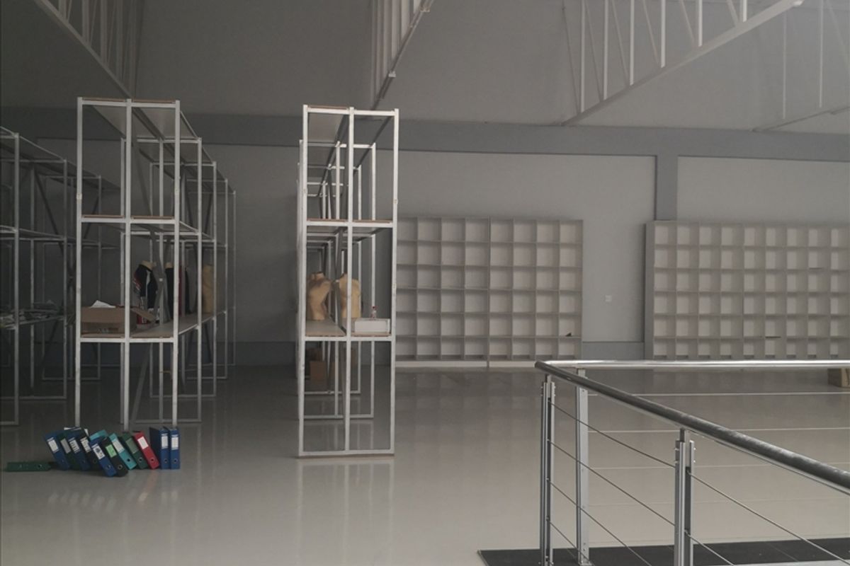 Spacious industrial utility area featuring high ceilings with exposed steel trusses, polished epoxy flooring, and extensive built-in metal shelving units.