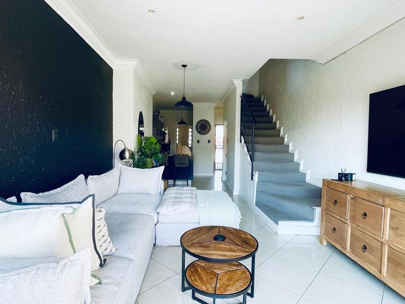 An open-plan living area featuring tiled flooring, recessed lighting, and a staircase leading to the upper level, creating a bright and functional space.
