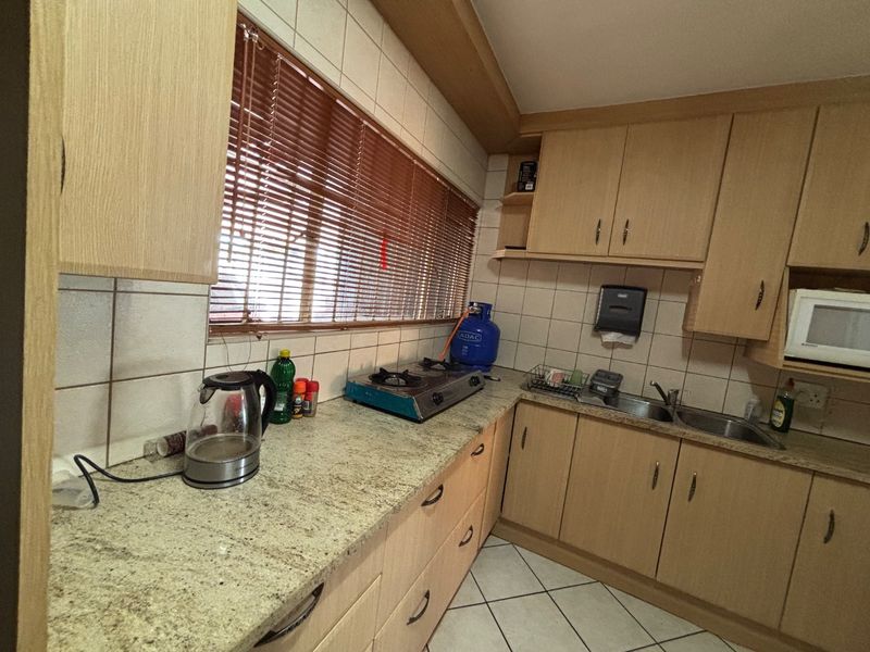 A functional kitchen featuring laminate cabinetry, granite countertops, a double basin sink, and tiled backsplash, offering a practical layout for daily meal preparation.