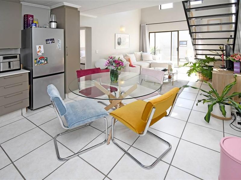 Open-plan living area featuring a modern kitchen with built-in cabinetry, tiled flooring, and a staircase leading to the upper level.